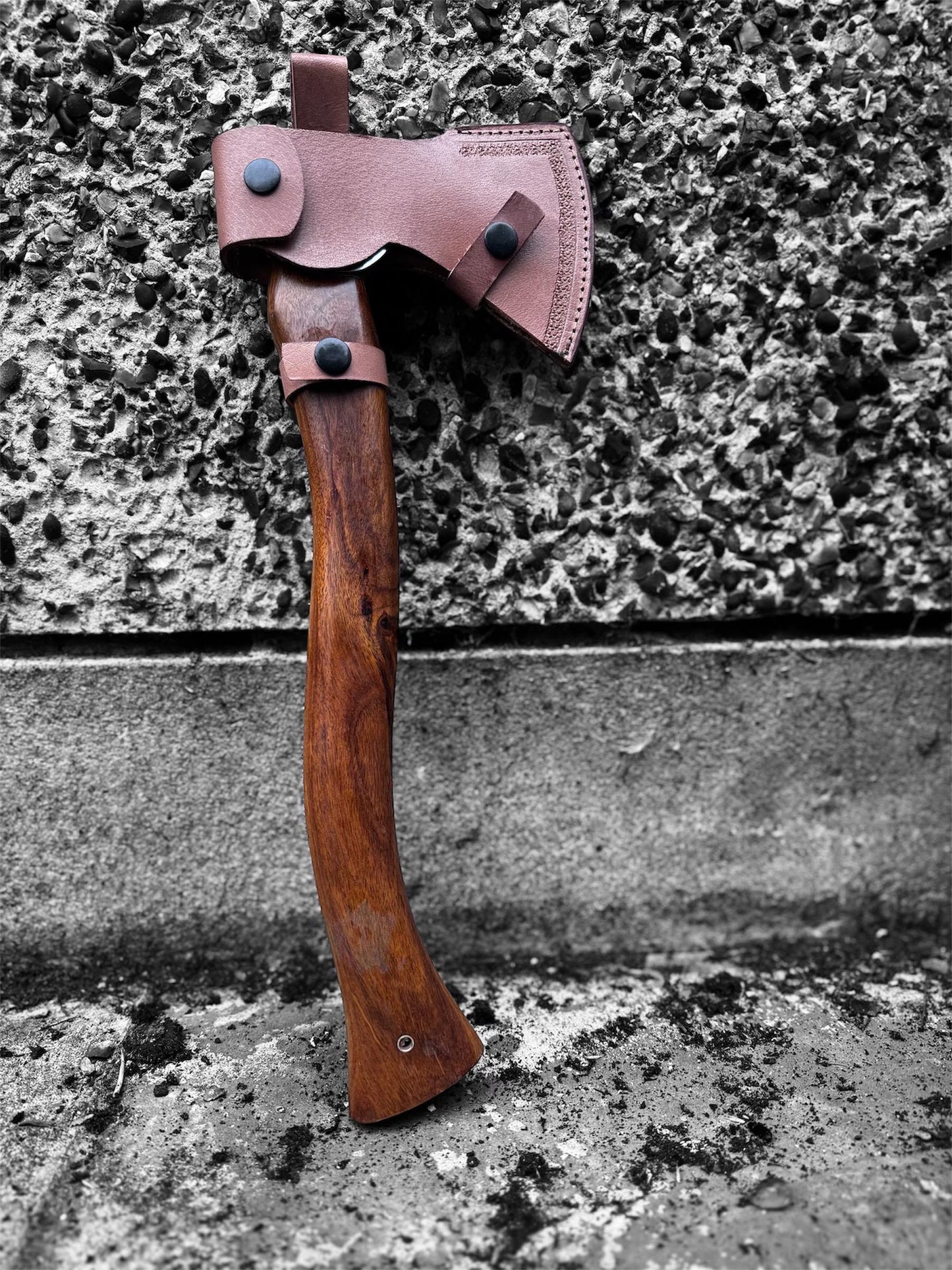 Wooden axe with leather sheath against a textured stone wall