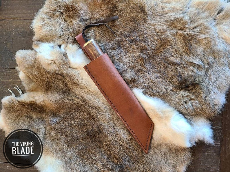 Damascus steel Seax knife featuring a polished walnut wood handle and leather sheath.