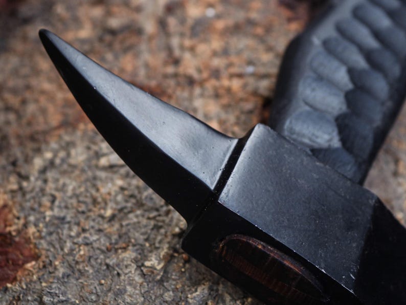 Close-up of a black metal tool with a pointed tip on a textured surface