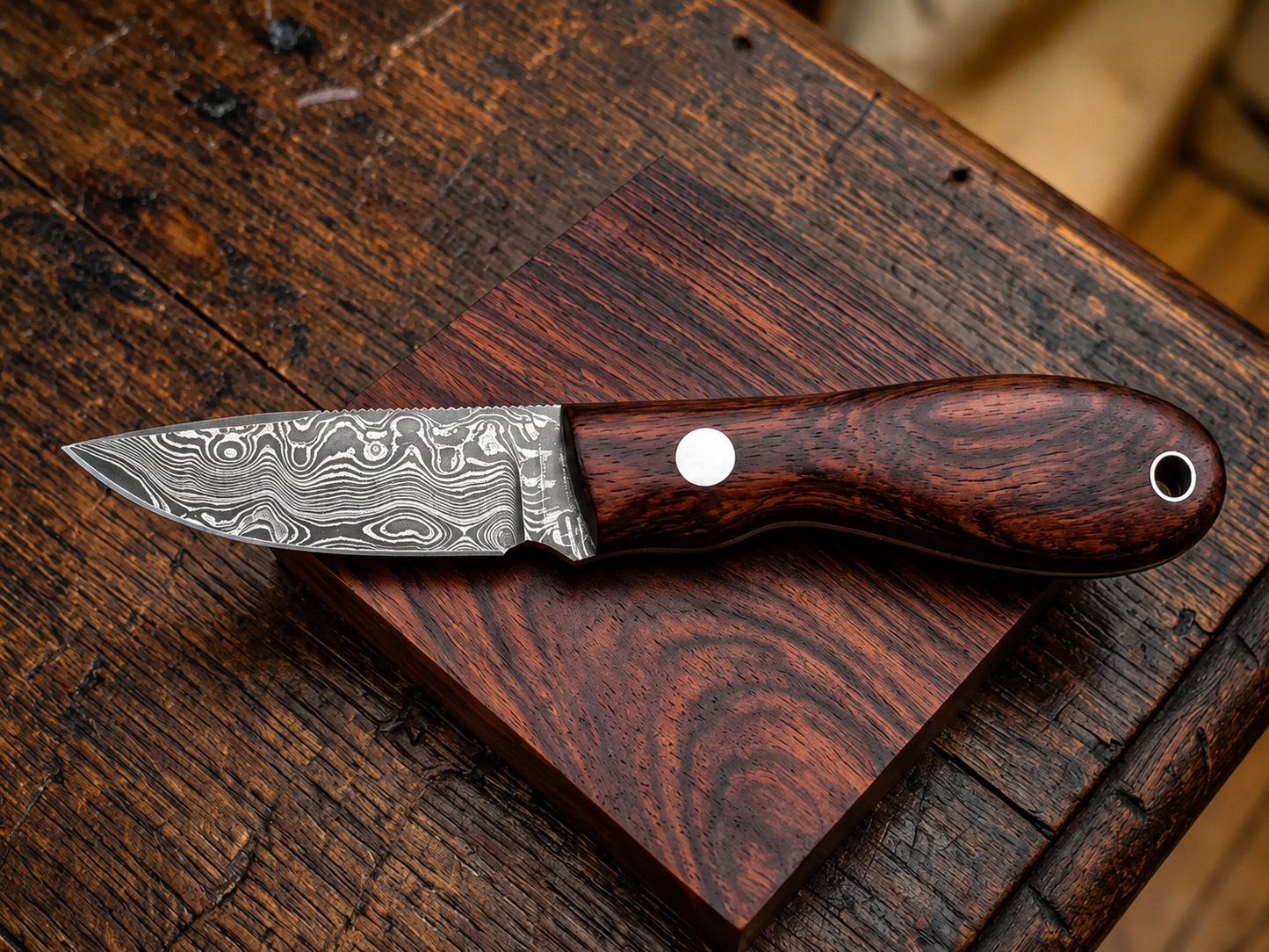 A fixed-blade knife with a patterned Damascus steel blade and a dark reddish-brown wooden handle, resting on a polished wooden block over a rustic wooden table.