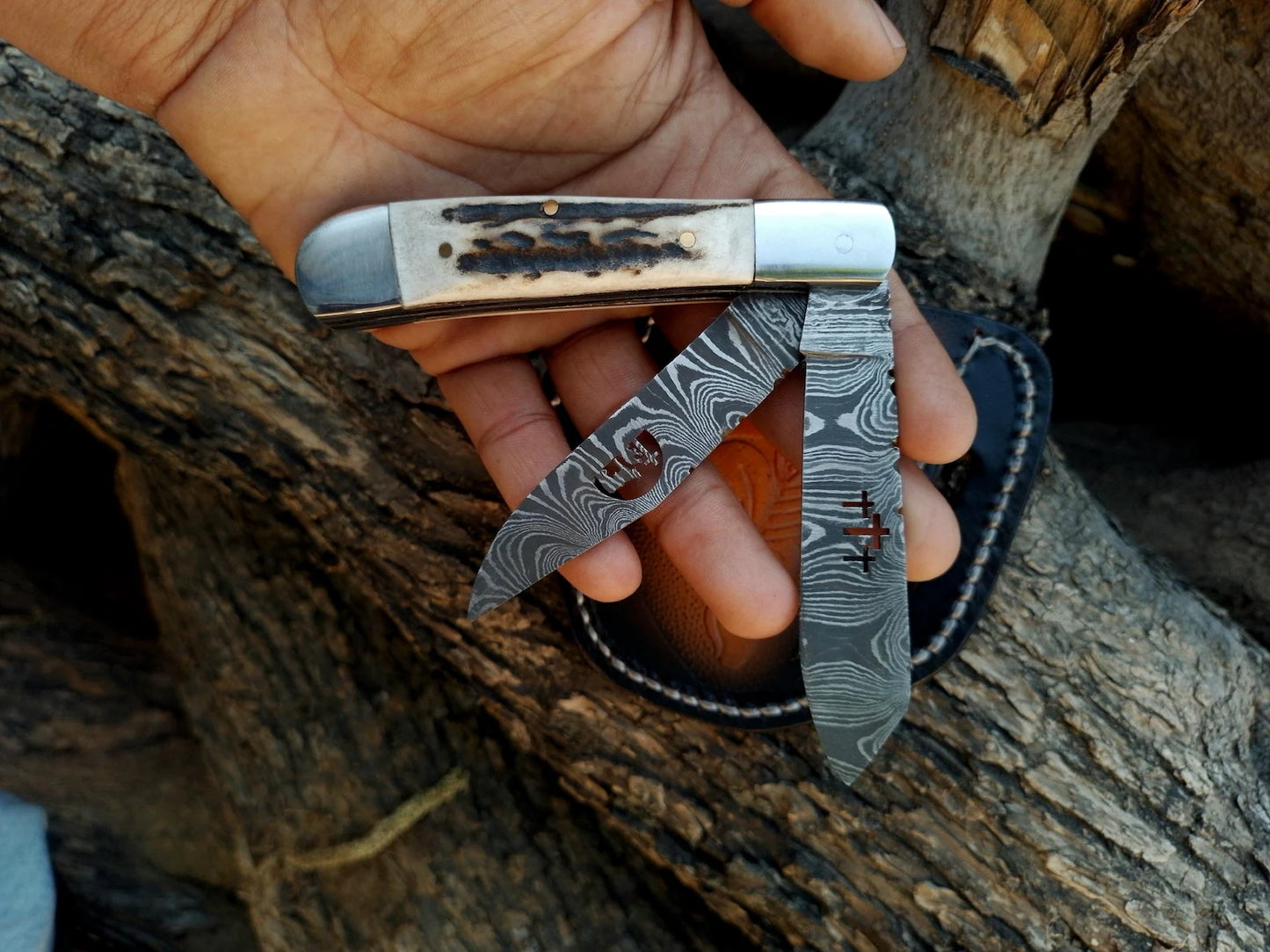 Hand holding a pocket knife with a wooden handle against a wooden background