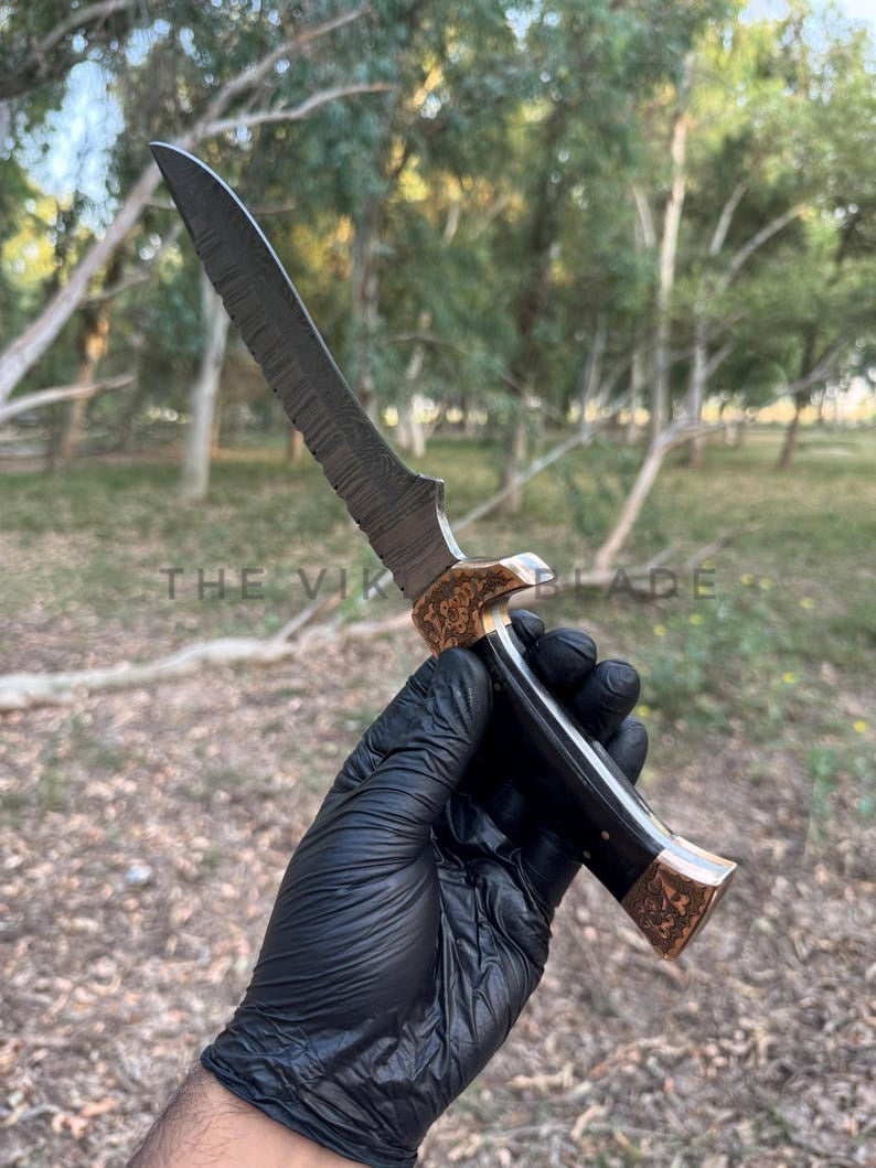Hand holding a knife with a forest background