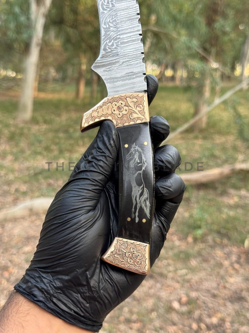 Decorative knife held by a gloved hand with a natural outdoor background