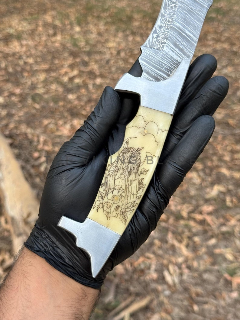 Hand holding a knife with decorative handle against a natural background