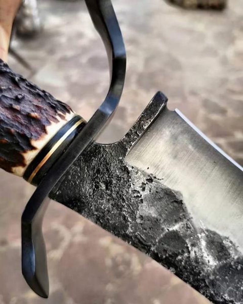 Close-up of a knife with a wooden handle and metal blade on a textured surface.