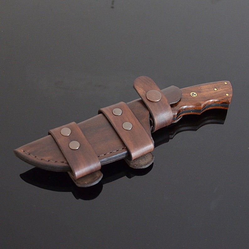 Brown leather knife sheath with wooden handle on dark background