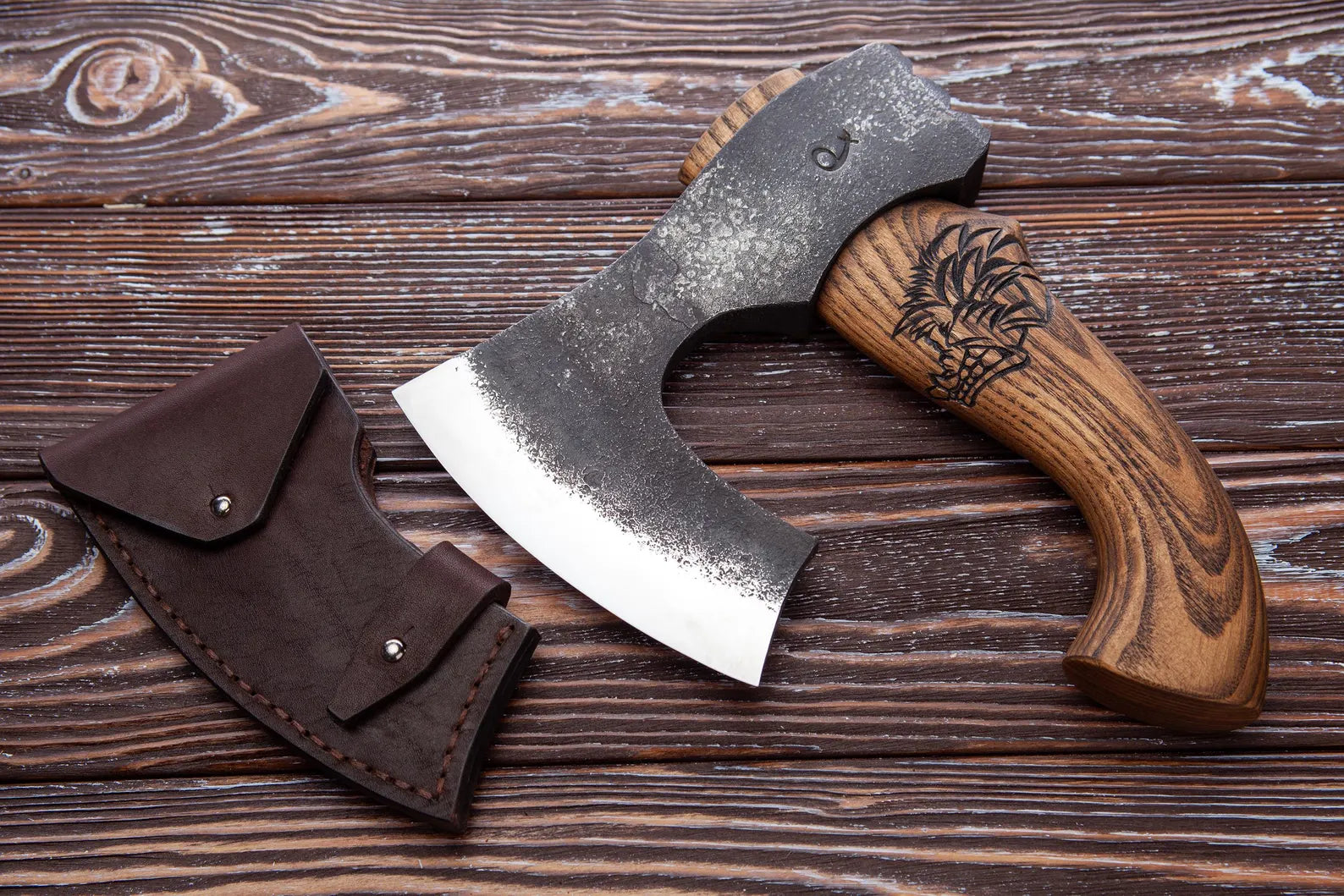 Wooden-handled axe with leather sheath on a wooden surface