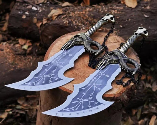 Two replica swords with intricate detailing, placed on a wooden stump, with a background of leaves and wood.