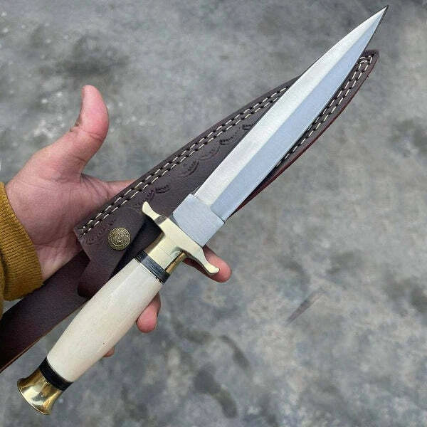 Hand holding a dagger with a leather sheath against a gray background