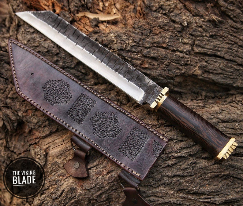 A carbon steel seax knife with a leather sheath, the knife features a dark brown handle with brass bolsters and a patterned blade.
