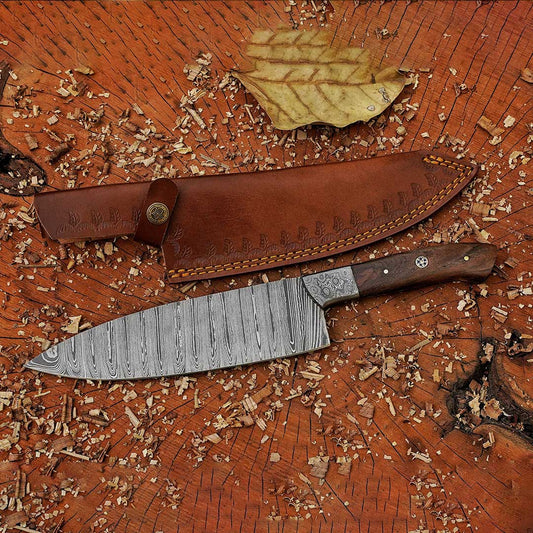 A 12-inch handmade Damascus chef knife with a dark walnut handle and a leather sheath, displayed on a wooden surface with some leaves nearby.