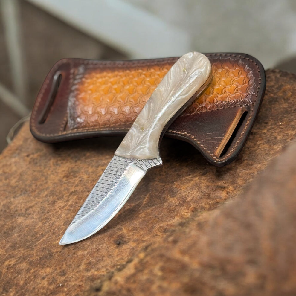 A stainless steel hunting knife with a striped pattern blade and a beige ergonomic resin handle, accompanied by a brown genuine leather loop case.