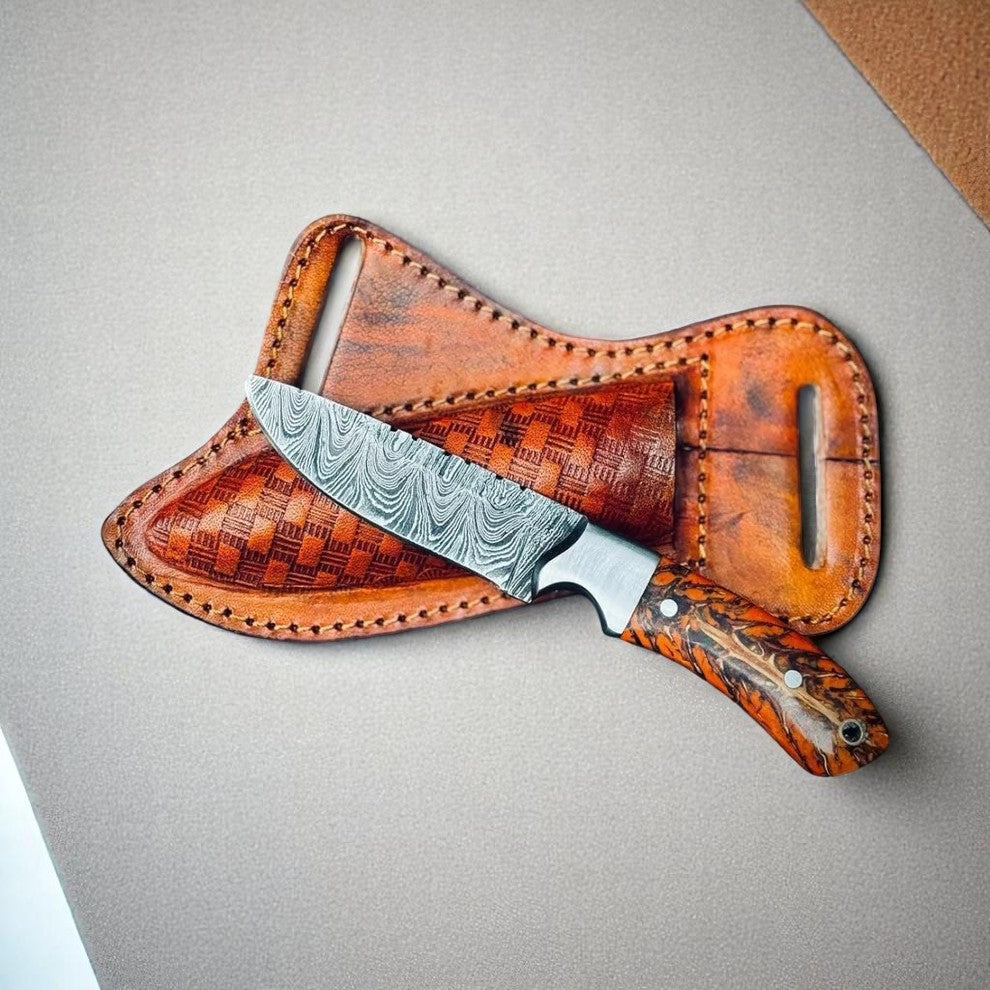 A brown leather knife sheath with a pine cone handle design, featuring a no-slip leather loop and a Damascus steel blade.
