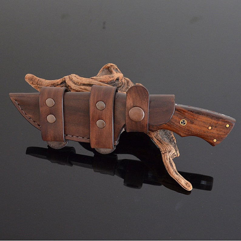 Wooden-handled knife with brown leather sheath on dark background