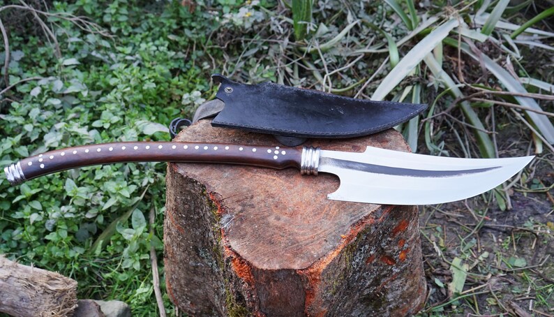 Decorative knife with a wooden handle on a wooden stump outdoors