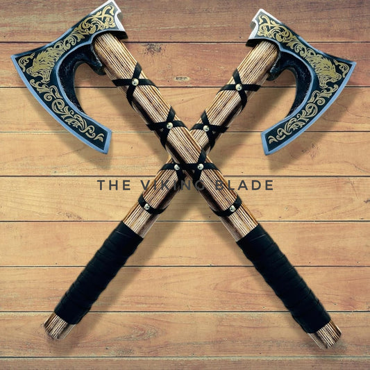 Two crossed axes with decorative handles on a wooden surface, branded 'The Viking Blade'.