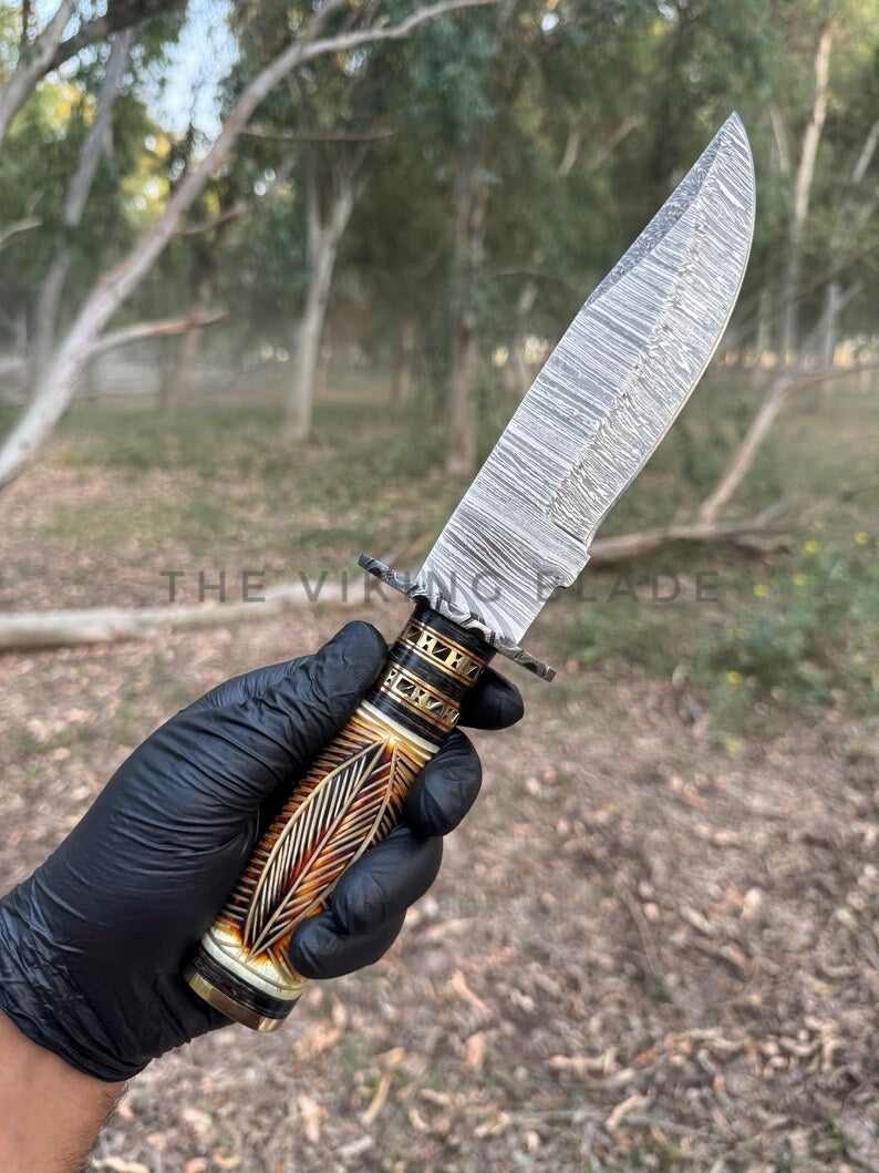 Knife with decorative handle held by a gloved hand against a natural background
