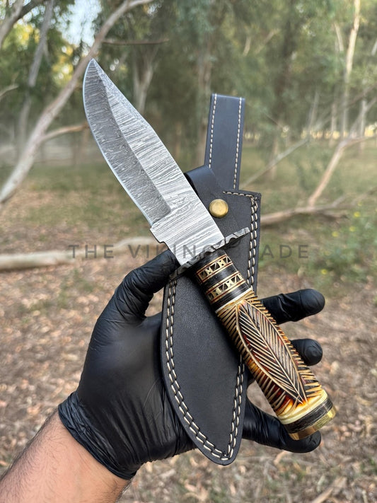 Knife with decorative handle held by a gloved hand against a natural background