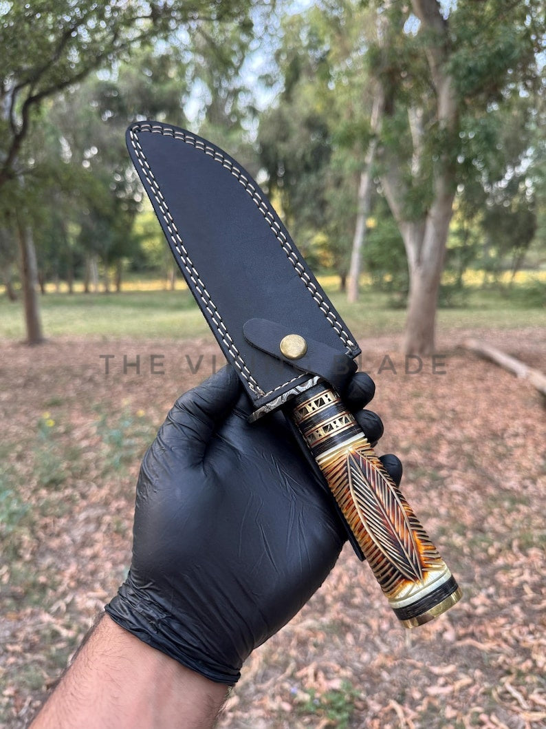 Hand holding a knife with a decorative handle in a natural setting