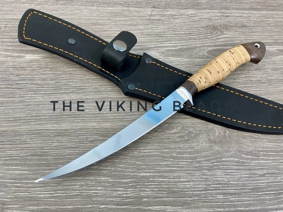 A hand forged fillet kitchen knife with a black leather sheath and a wooden handle.