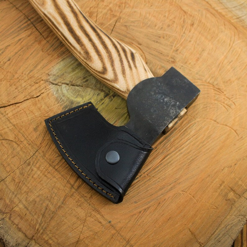 Small axe with a black leather sheath on a wooden surface