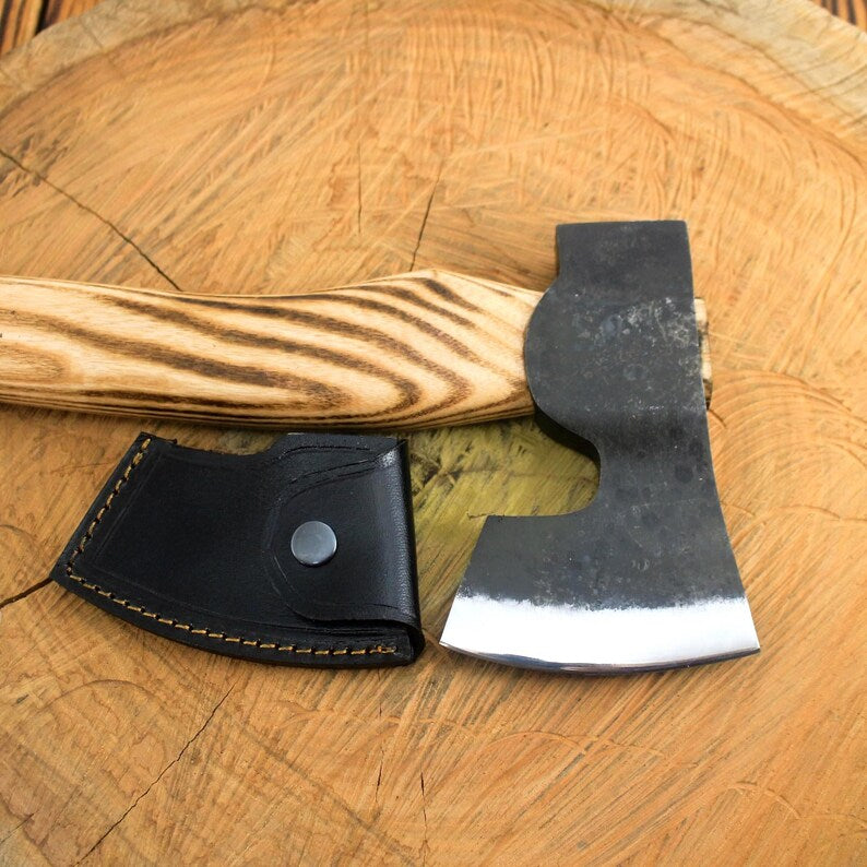 Wooden-handled axe with a black leather sheath on a wooden surface