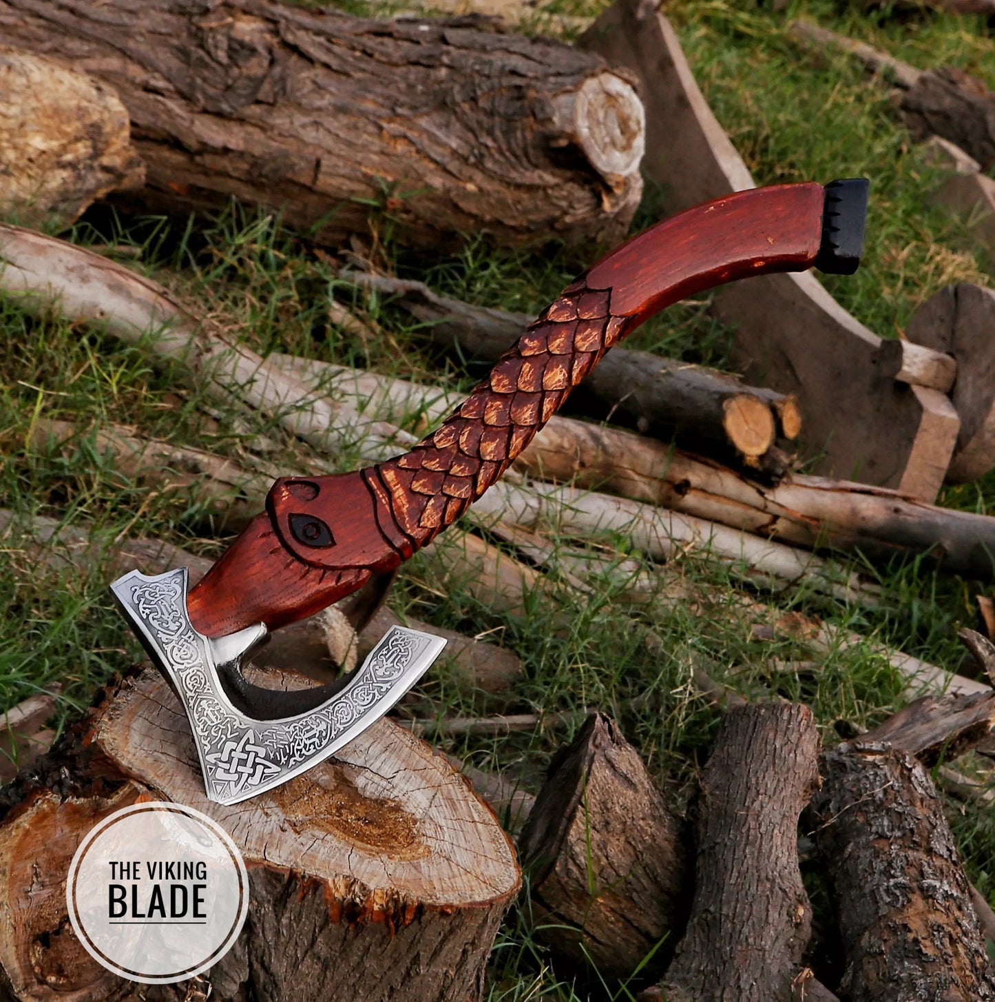 A handmade carbon steel Viking axe with a brown ashwood handle and a leather sheath, placed on a wooden stump with a natural outdoor background.