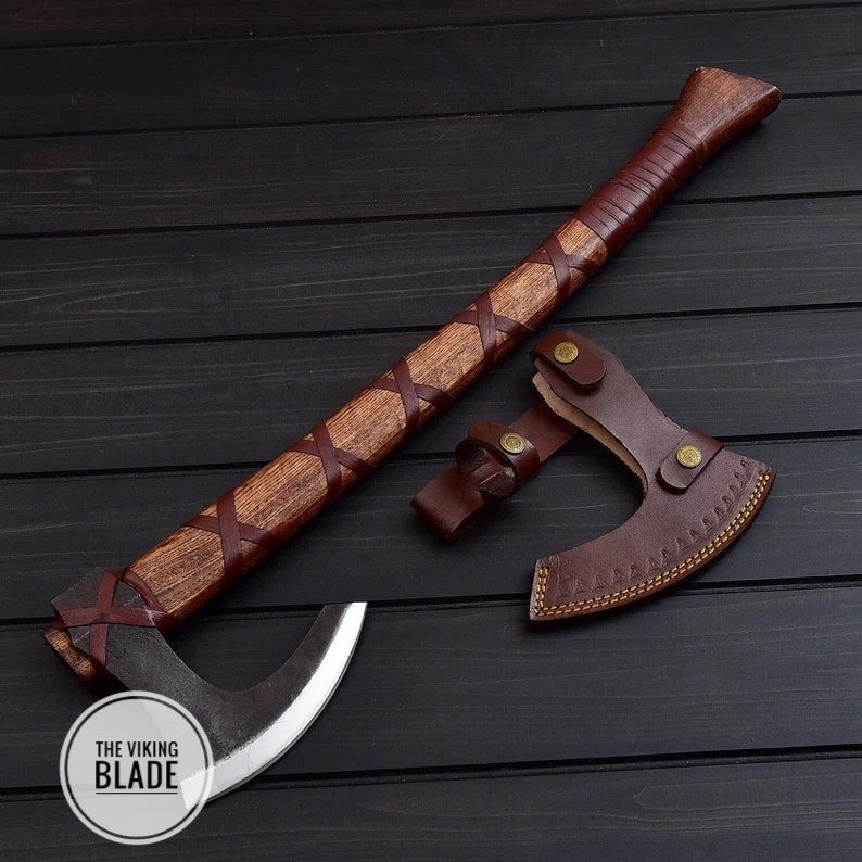 A handmade carbon steel axe with a leather sheath, the axe has a brown and black handle with a patterned head and a leather pouch attached to the blade.