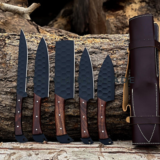 A collection of custom handmade chef knives with a leather roll kit. The knives have black handles with a textured grip and brown leather accents.