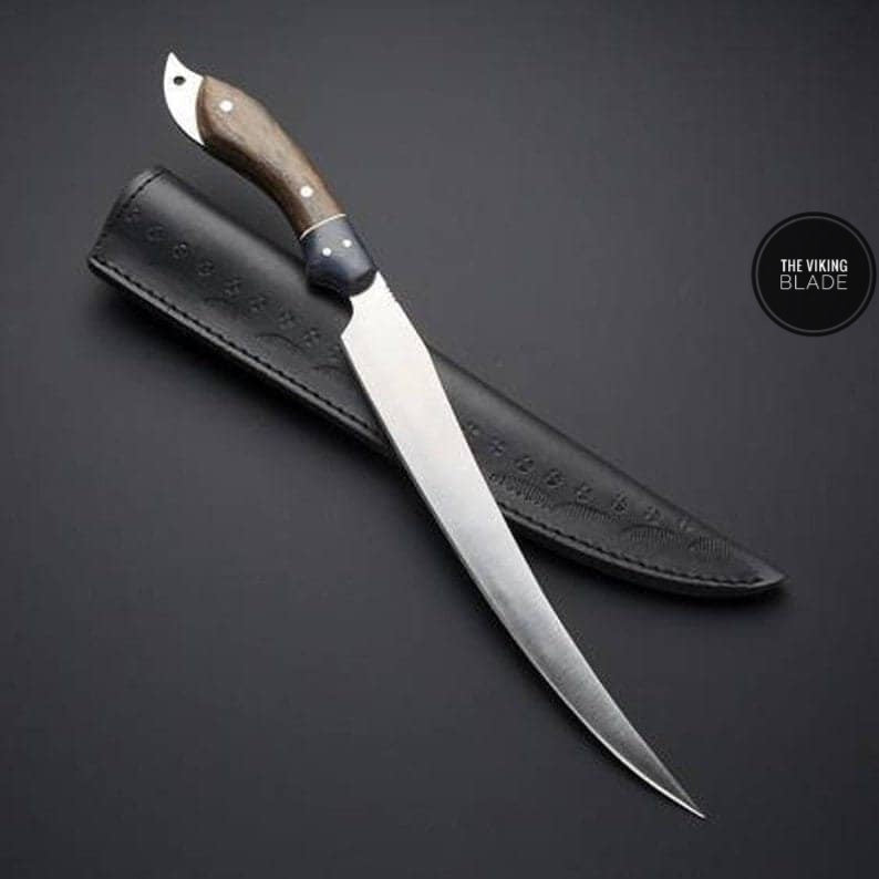 A custom handmade D2 steel fillet fish hunting knife with a wooden handle and a leather sheath, displayed on a dark background.