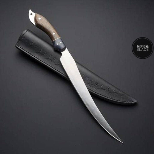 A custom handmade D2 steel fillet fish hunting knife with a wooden handle and a leather sheath, displayed on a dark background.