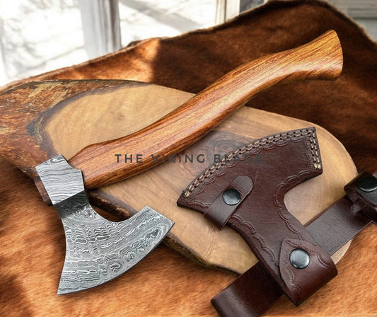 Decorative axe with wooden handle and leather sheath on a wooden surface