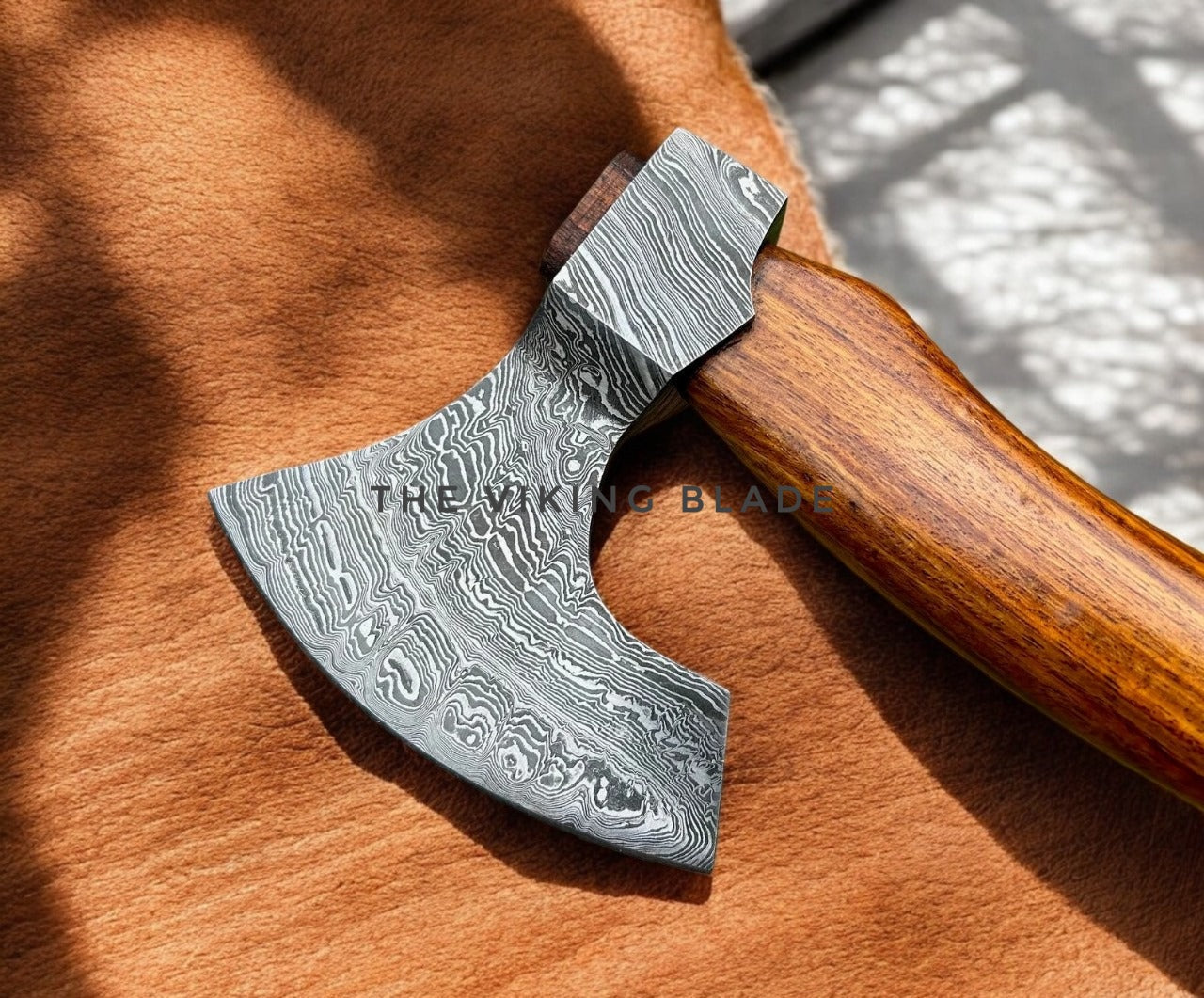 Decorative axe with wooden handle on a brown surface, branded 'The Viking Blade'.