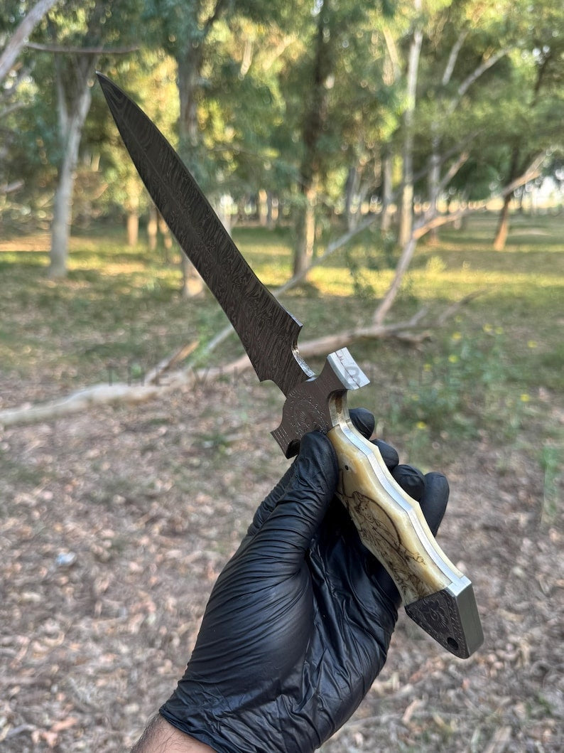 Hand holding a knife with a wooden handle outdoors