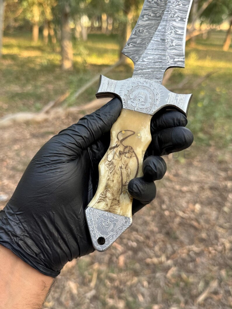 Hand holding a large knife with a detailed blade and gold handle, wearing black gloves, outdoors.