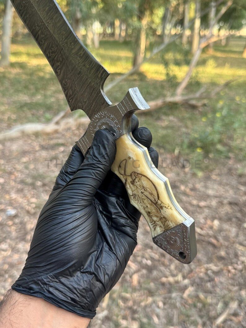Hand holding a large knife with a detailed handle outdoors