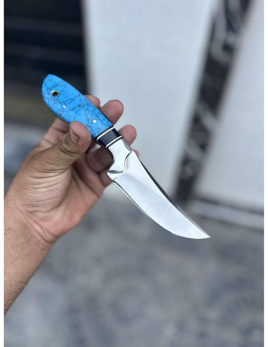 Hand holding a knife with a blue handle against a blurred background