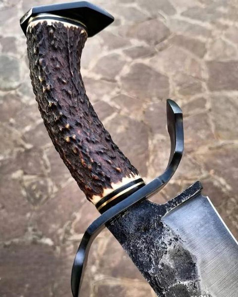 Close-up of a dagger with a wooden handle and metal sheath against a stone wall background.