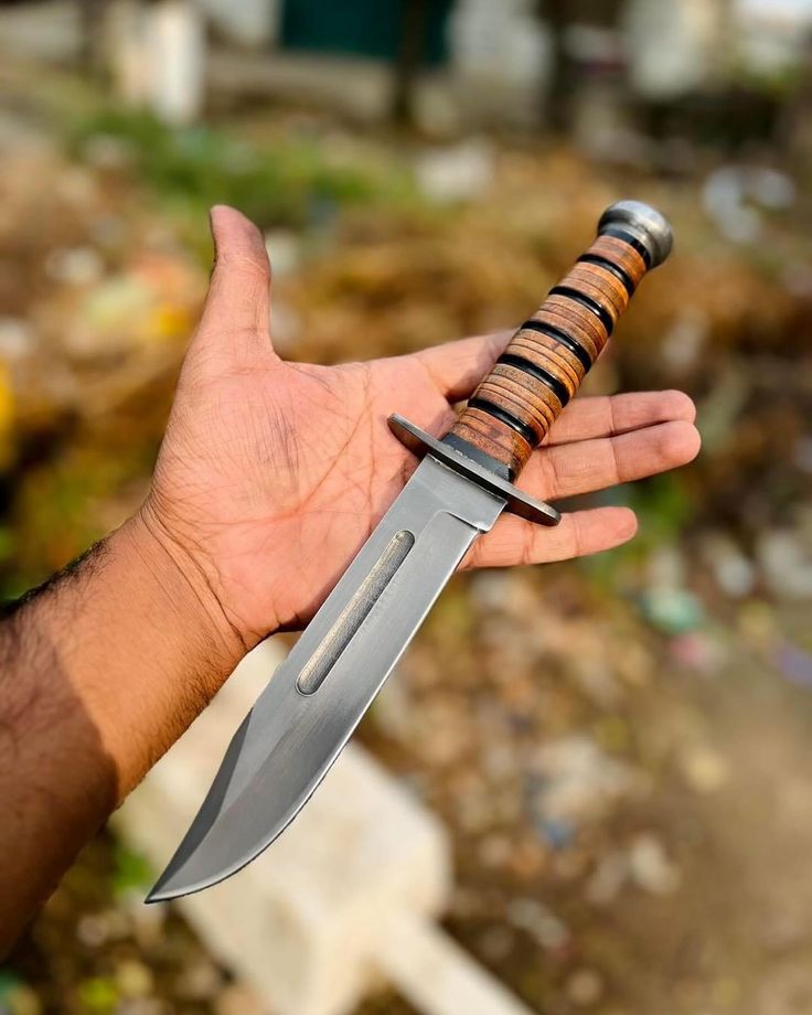 Hand holding a knife with a wooden handle against a blurred background
