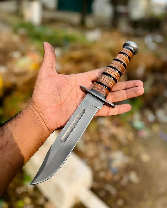 Hand holding a knife with a wooden handle against a blurred background