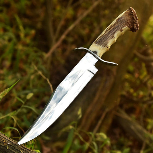 A handmade hunting Bowie knife with a silver blade and a brown and white handle, displayed outdoors.
