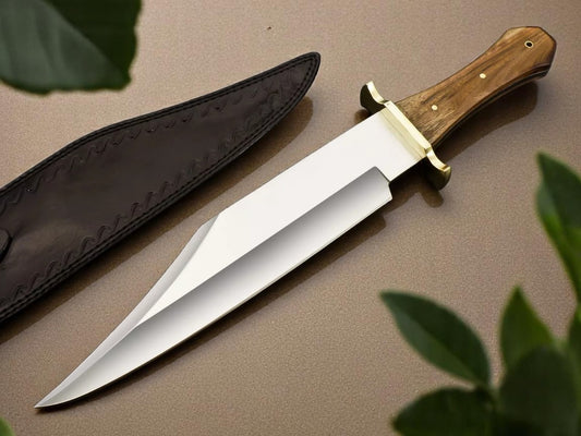 A custom handmade hunting Bowie knife with a walnut wood handle and a brass finger guard, accompanied by a black leather sheath. The knife has a smooth, polished blade with a visible grain pattern on the handle.