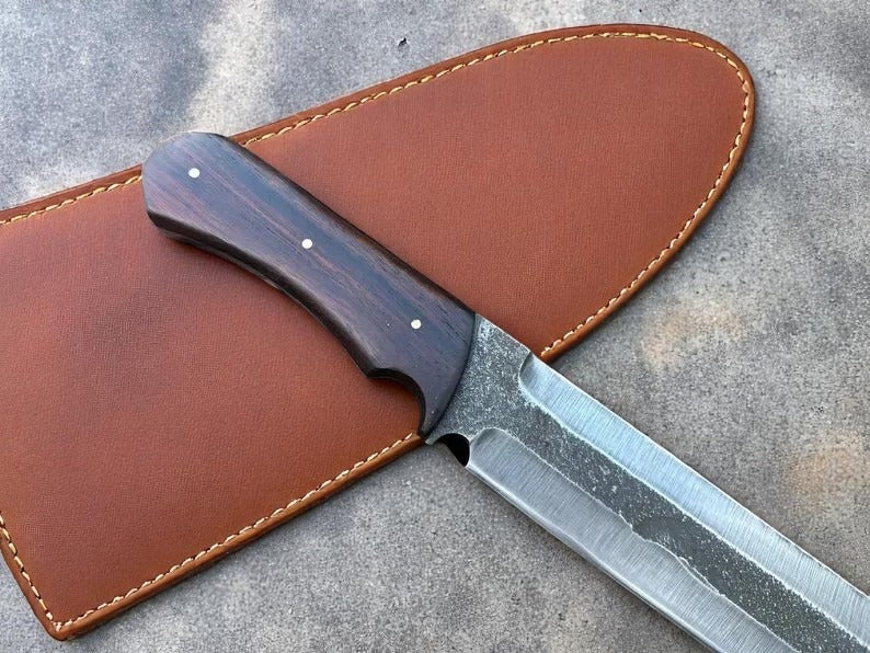 Knife with wooden handle in a brown leather sheath on a concrete surface.
