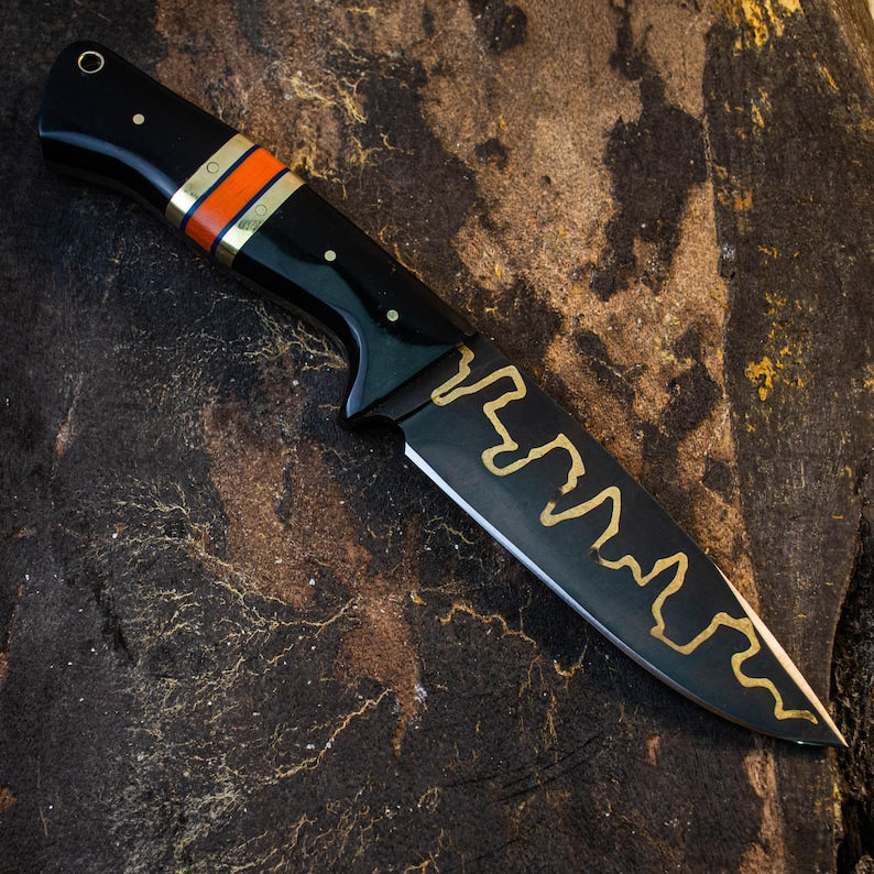 Forked blade knife with black handle and orange accent on a textured background