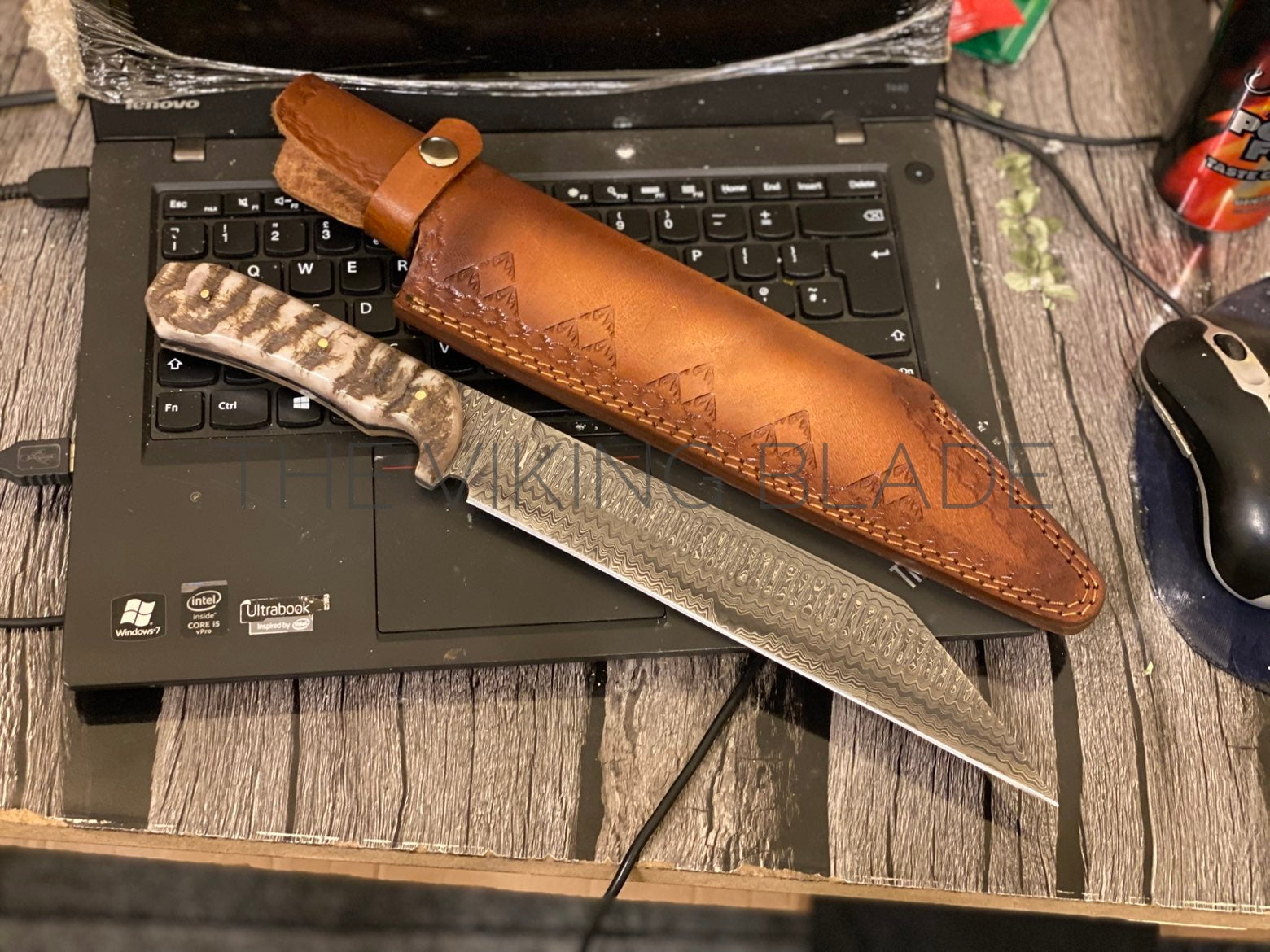 Knife with leather sheath on a laptop keyboard