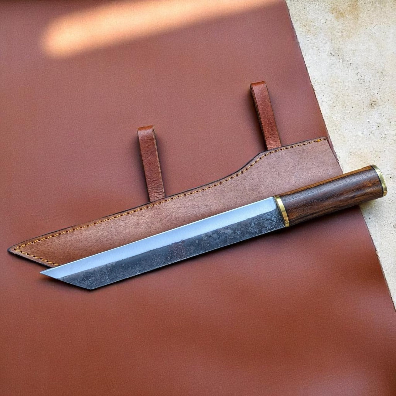 A custom handmade seax knife with a brown wooden handle and a Damascus patterned blade, accompanied by a brown leather sheath.