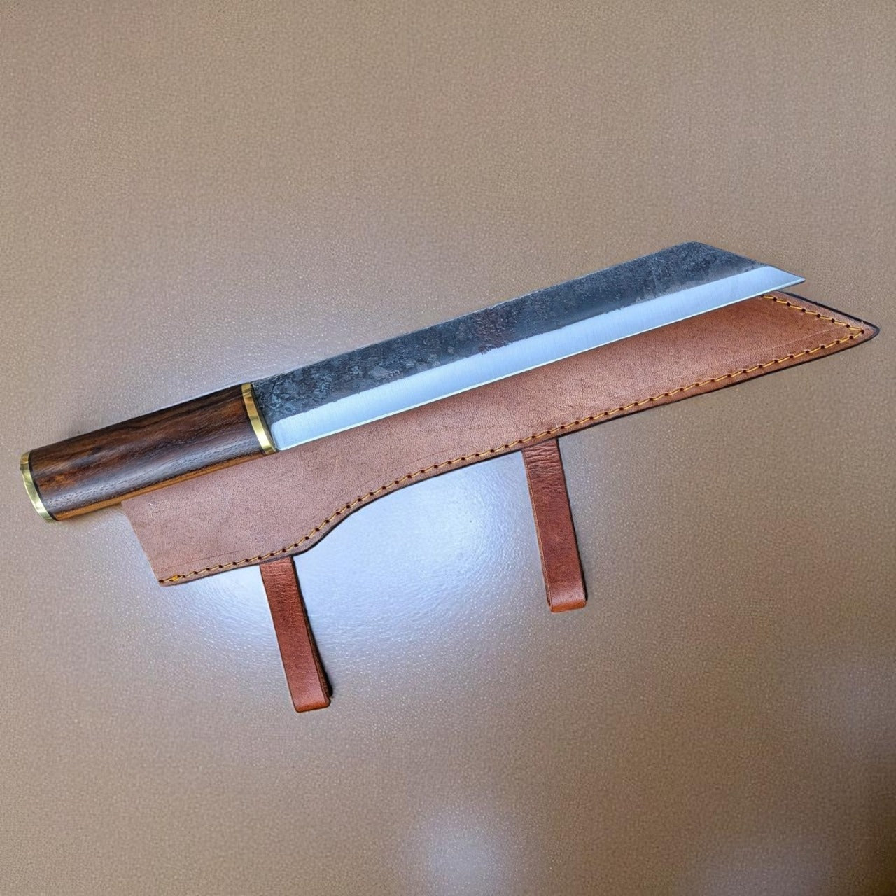 Knife with brown handle and leather sheath on neutral background