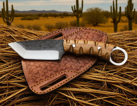 Two knives with wooden handles and leather sheaths on a hay background with cacti in the background