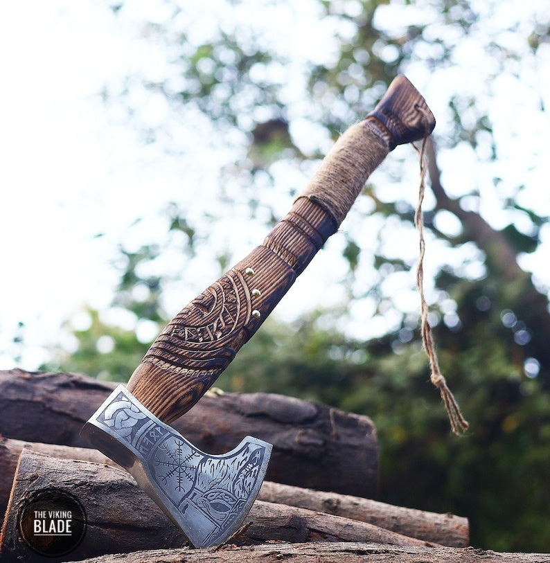 A handmade Viking axe with a leather sheath, featuring a carbon steel blade and a wooden handle with a decorative pattern.