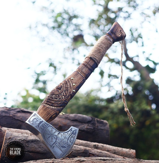 A handmade Viking axe with a leather sheath, featuring a carbon steel blade and a wooden handle with a decorative pattern.